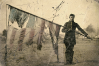 A soldier holds a tattered American flag
